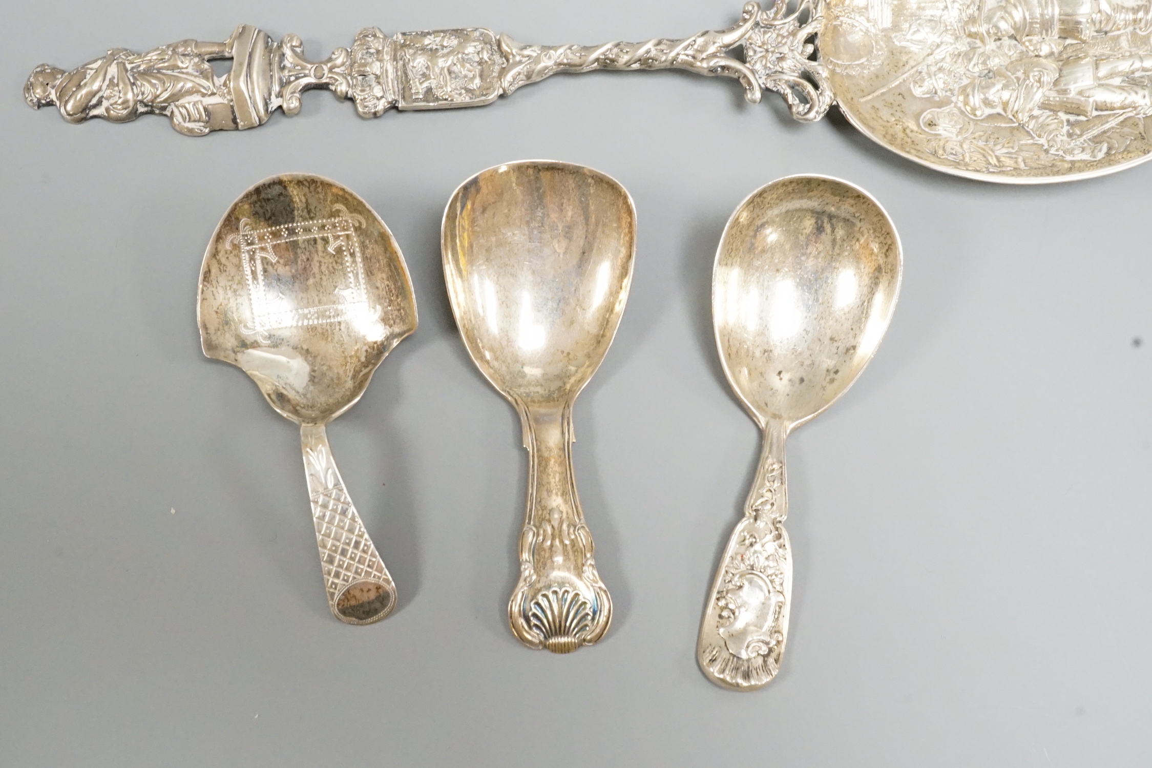 Two 19th century silver caddy spoons, including Birmingham, 1827, one later caddy spoon and an ornate Dutch white metal serving spoon.